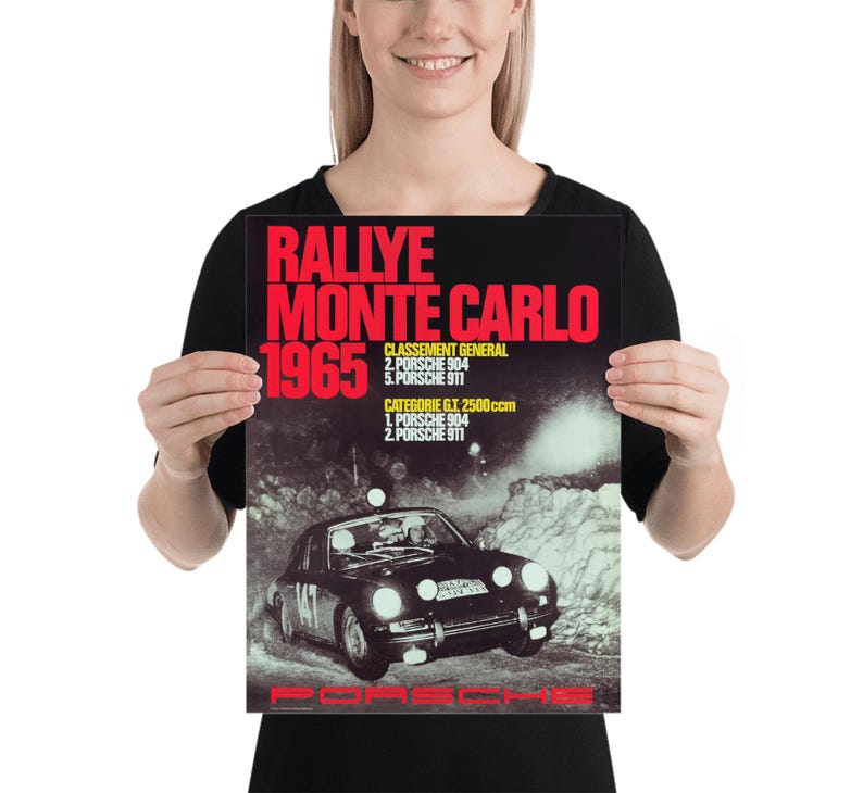 May include: Poster depicting a vintage car racing scene. The poster has the text "RALLYE MONTE CARLO 1965" in red and white. A black Porsche car is shown racing on a snowy road. The poster also lists the race results.