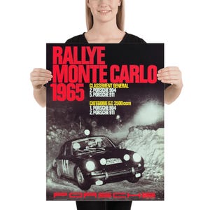 May include: Poster depicting a vintage Porsche race car in a snowy scene. The poster displays the text "RALLYE MONTE CARLO 1965" in red, with race results. The Porsche logo is at the bottom of the poster.