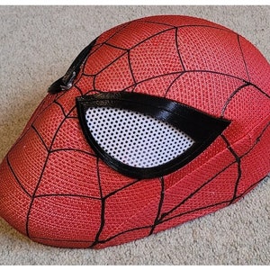 May include: A red and black Spider-Man mask with a mesh eye opening. The mask is made of a textured fabric and has a 3D design.