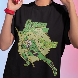 Puede incluir: Camiseta negra con un gráfico verde y amarillo de Green Arrow, el Arquero Esmeralda, apuntando una flecha a un objetivo.