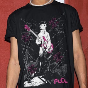 Puede incluir: Camiseta negra con un estampado gráfico de un personaje de anime sosteniendo una guitarra eléctrica rosa. El gráfico incluye el texto "FLCL".