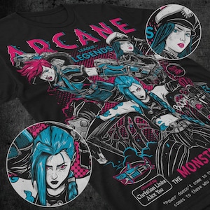 Puede incluir: Una camiseta negra con un diseño gráfico que presenta personajes del videojuego League of Legends. El diseño incluye el texto "Arcane League of Legends" y "The Monster" con la cita "El poder no llega a quienes llegan al poder".