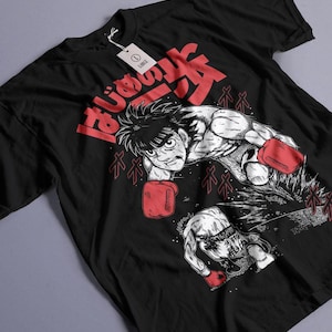 May include: Black t-shirt featuring a dynamic illustration of a boxer in action, wearing red gloves. Japanese text in red is at the top. A tag with the word "LARGE" is attached to the shirt.