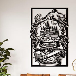 May include: Black metal wall art featuring a castle within a snow globe, set upon open books. The design incorporates a mountain, moon, and floral details, enclosed in a rectangular frame. The text "EYWA WALL DECORS" is visible.