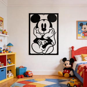 Könnte beinhalten: Schwarz-weiße Mickey Mouse Wandkunst. Das Kunstwerk zeigt einen lächelnden Mickey Mouse mit den Händen unter dem Kinn. Die Kunst ist in einem schwarzen Rahmen eingefasst und hängt an einer weißen Wand. Ein Mickey Mouse Plüschtier liegt auf dem Boden.