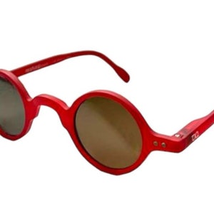 Może przedstawiać: Okulary przeciwsłoneczne w okrągłym kształcie, w kolorze czerwonym z brązowymi szkłami. Okulary mają prosty, klasyczny design.