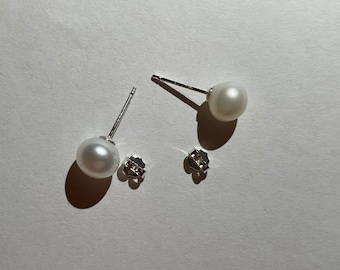 Peut inclure: Une paire de boucles d'oreilles en perles avec des tiges et des dos en argent. Les perles sont blanches et rondes.