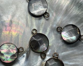 May include: Five round, iridescent, mother-of-pearl, connector charms with gold-toned metal loops. The charms are on a white, iridescent, mother-of-pearl surface.