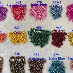 Peut inclure: Une collection de petites perles rondes de différentes couleurs : violet, orange, rose, rose bébé, gris ciel, rose, orange, or, vert, rouge foncé, ambre, bronze, vert herbe, chocolat, bleu lac et prune clair. Chaque couleur est étiquetée avec un numéro.