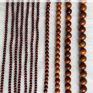 May include: Multiple strands of round, dark brown wooden beads arranged in vertical rows. The image displays labels indicating bead diameters of 4mm, 6mm, 8mm, 10mm, and 12mm, showing the varying sizes of the beads from smallest to largest.