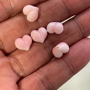 Puede incluir: Colección de seis cuentas en forma de corazón de color rosa claro. Las cuentas tienen una superficie lisa y pulida y están diseñadas con un agujero para ensartar. Las cuentas son de un color rosa pastel suave.