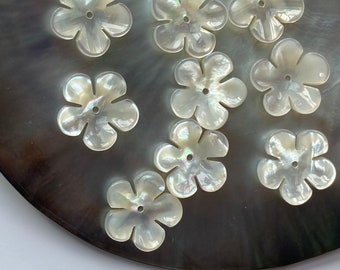 May include: Ten white mother of pearl flower-shaped buttons with a hole in the center.