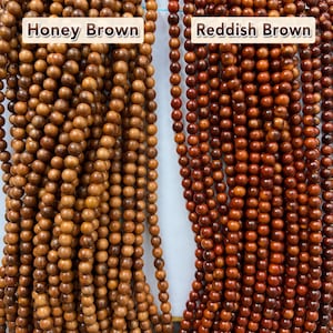 May include: Two vertical strands of round wooden beads. The left strand is labeled Honey Brown and features light tan, smooth beads. The right strand is labeled Reddish Brown and consists of darker, deep mahogany-colored wooden beads.