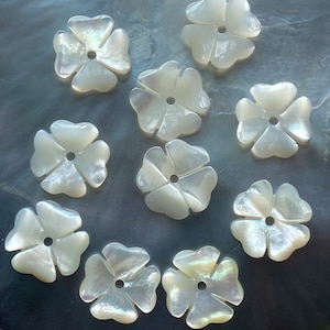 May include: Ten white mother of pearl flower shaped buttons with a hole in the center.