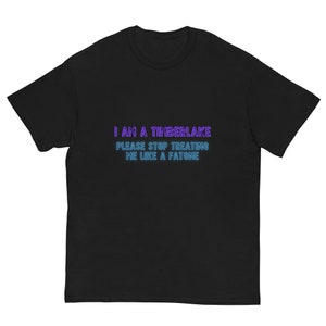 Puede incluir: Camiseta negra con el texto "I AM A TIMBERLAKE PLEASE STOP TREATING ME LIKE A FATONE" en letras de neón morado y azul.
