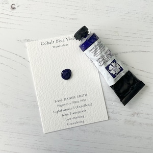 May include: A tube of Daniel Smith Extra Fine Watercolour in Cobalt Blue Violet, with a swatch of the paint and a card with details. The tube is dark blue with white text and a black cap. The card lists pigment information.