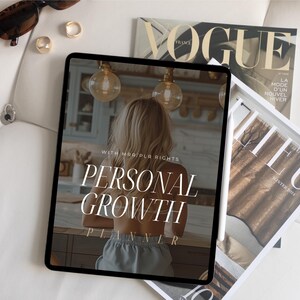 May include: A digital tablet displaying a personal growth planner with the text "WITH MAR/PLA RIGHTS PERSONAL GROWTH PLANNER". The tablet is on a white surface with a magazine and sunglasses.