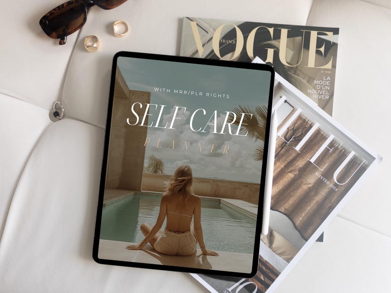 K&ouml;nnte beinhalten: Ein digitales Tablet zeigt einen Selbstpflege-Planer mit dem Text "Self Care Planner" und "With MRR/PLR Rights". Das Tablet liegt auf einer wei&szlig;en Oberfl&auml;che mit einem Magazin und einer Sonnenbrille.