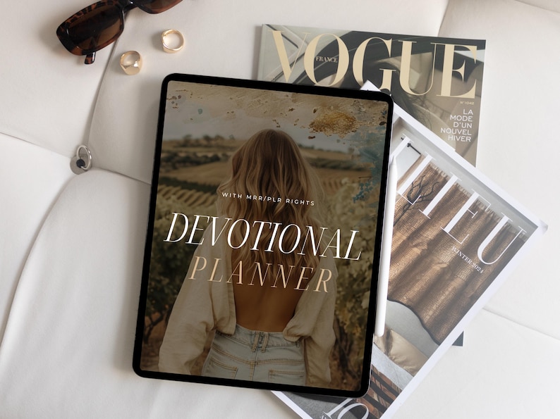 May include: A digital tablet displaying a devotional planner with the text "WITH MARRIED RICHES DEVOTIONAL PLANNER" on a white background. The tablet is surrounded by magazines.