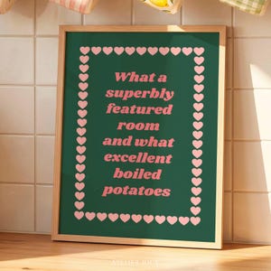 Puede incluir: Un cuadro enmarcado con fondo verde y texto rosa: "What a superbly featured room and what excellent boiled potatoes". El borde está adornado con corazones rosas.