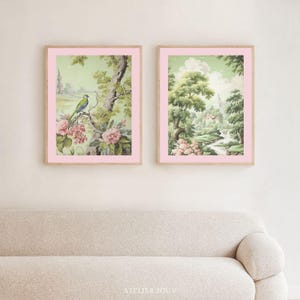 Dreamy sage green wall art in two coordinated digital prints. One features a green bird perched on a flowering branch with pink peonies and a stone tower in the distance. The other captures a romantic landscape of tall trees, soft clouds, a river and a cottage nestled in the greenery. Print-ready in all major ratios. Instant download, no physical item.