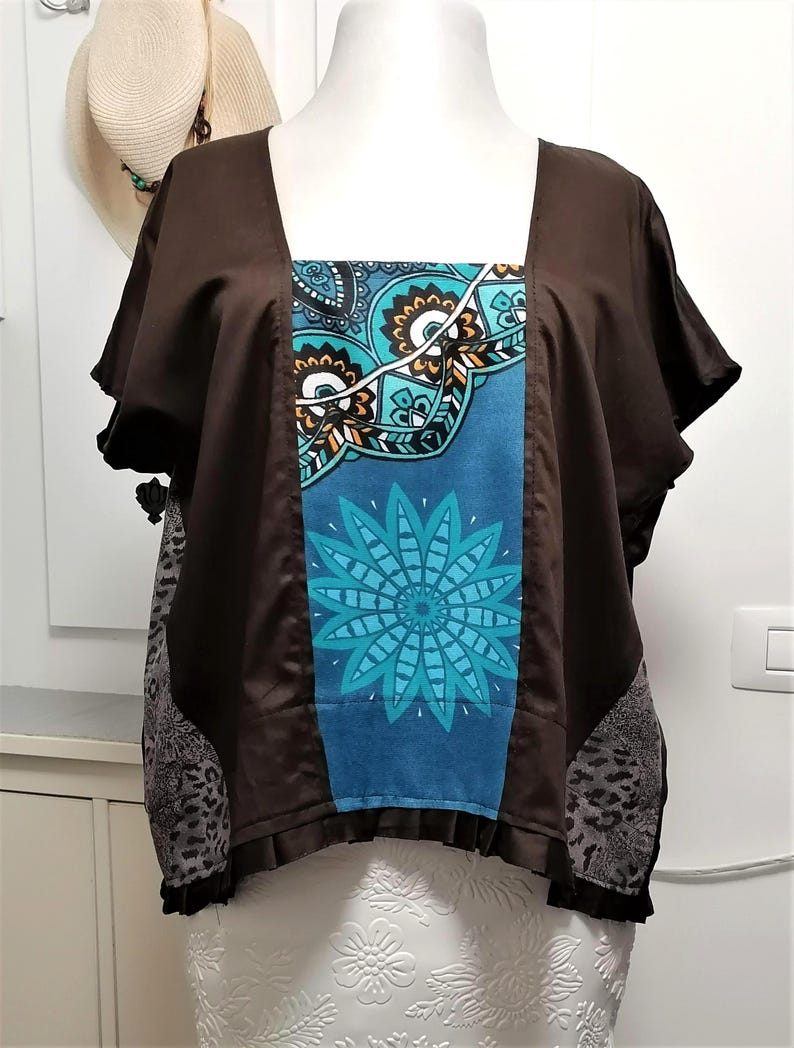 May include: A brown square-neck top with short sleeves. The front panel features a blue and teal floral design. The sides have a grey and black animal print. The top is displayed on a mannequin.