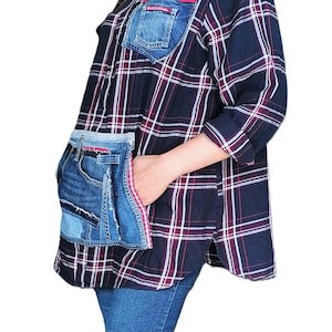 Op de afbeelding: Een overhemd met lange mouwen en knoopsluiting, voorzien van een ruitpatroon in donkerblauw, wit en rood. Het overhemd is versierd met gerecyclede blauwe denim stoffen, waaronder een borstzak met rode bies en een grote zijzak.