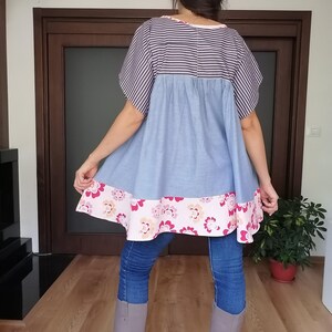 May include: A blue and white striped top with a light blue skirt and a floral patterned hem. The top is paired with blue jeans and grey boots. The outfit is casual and comfortable.