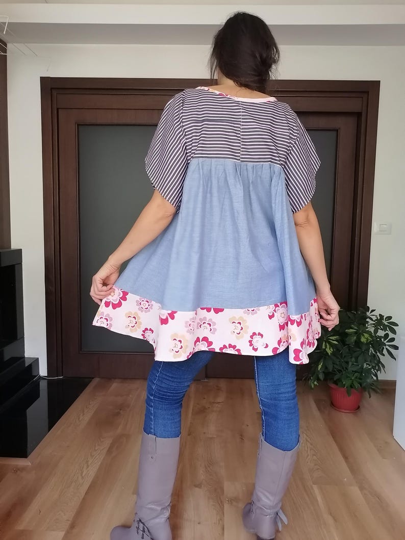 May include: A blue and white striped top with a light blue skirt and a floral patterned hem. The top is paired with blue jeans and grey boots. The outfit is casual and comfortable.