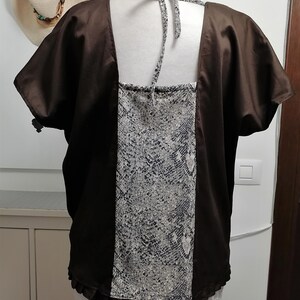 May include: A brown satin top with short sleeves and a square neckline. The back features a panel of grey and white snakeskin print fabric. The top is displayed on a mannequin.