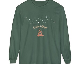Op de afbeelding: Een lange mouwen, donkergroen shirt met een afbeelding van een kampvuur en sterren. De tekst "Campfires & Starlight" staat boven het kampvuur. Het shirt is gemaakt van een zacht materiaal. Een casual top voor buitenliefhebbers.
