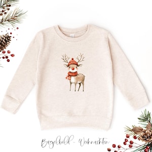 Könnte beinhalten: Beiges Sweatshirt mit einer Aquarellillustration eines Rentiers mit roter Mütze und Schal. Das Rentier hat ein Geweih und eine rote Nase. Der Text "Bügelbild - Weihnachten" ist unten in Kursivschrift geschrieben. Festliche Kleidung.