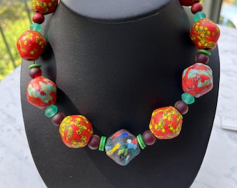 Halsband. Unikt smycke. Djärvt. Färgglatt. Tribalt, afrikanskt, etniskt, återvunnet glas, mycket dekorativt, rött (gult och grönt). Iögonfallande smycke.