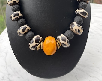 Halsband. Tribal, afrikanskt, etniskt, svart/vitt/orange. Batik (benpärlor), orange hartspärla, mässingsringar, unikt, iögonfallande föremål.