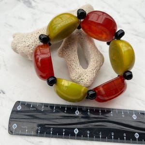 May include: A bracelet made of large, round, green and red beads with black spacers. The bracelet is about 7 inches in diameter.