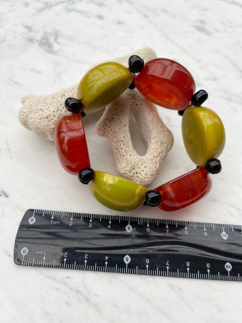 May include: A bracelet made of large, round, green and red beads with black spacers. The bracelet is about 7 inches in diameter.