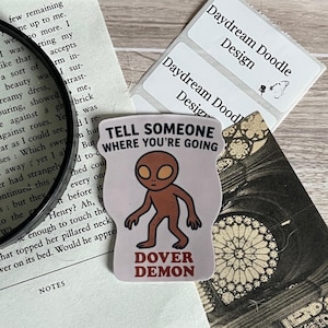 May include: A sticker with a brown alien-like figure walking with the text "Tell someone where you're going" and "Dover Demon" below the figure.