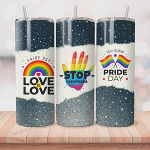 Puede incluir: Tres vasos de acero inoxidable con tapas y pajitas. Cada vaso presenta un diseño con un arcoíris, las palabras "Love is Love" y "Pride Day". Un vaso tiene una mano con la palabra "Stop" y "Homofobia".