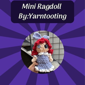 May include: A crocheted mini ragdoll with bright red yarn hair, a blue dress with white trim, and button eyes. The doll features a small blue bow on top of its head. The text "Mini Ragdoll By:Yarntooting" is displayed in a dark rectangular box above.