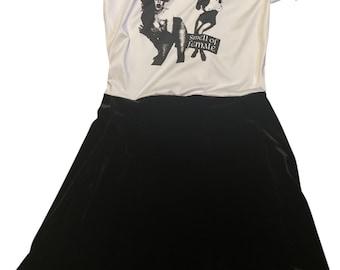 May include: White t-shirt with a black and white image of a band called "The Cramps" and the text "Smell of Female". The t-shirt is paired with a black velvet skirt.