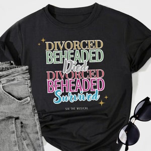 May include: Black t-shirt with colourful text that reads "Divorced, Beheaded, Died, Divorced, Beheaded, Survived" and "Six the Musical" at the bottom.