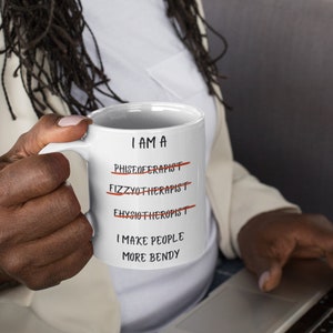 A white 11oz ceramic coffee mug for Physiotherapists with the funny caption "I am a Physiotherapist" But it is crossed out three times miss spelt. The caption then says at the bottom "I make people more bendy"