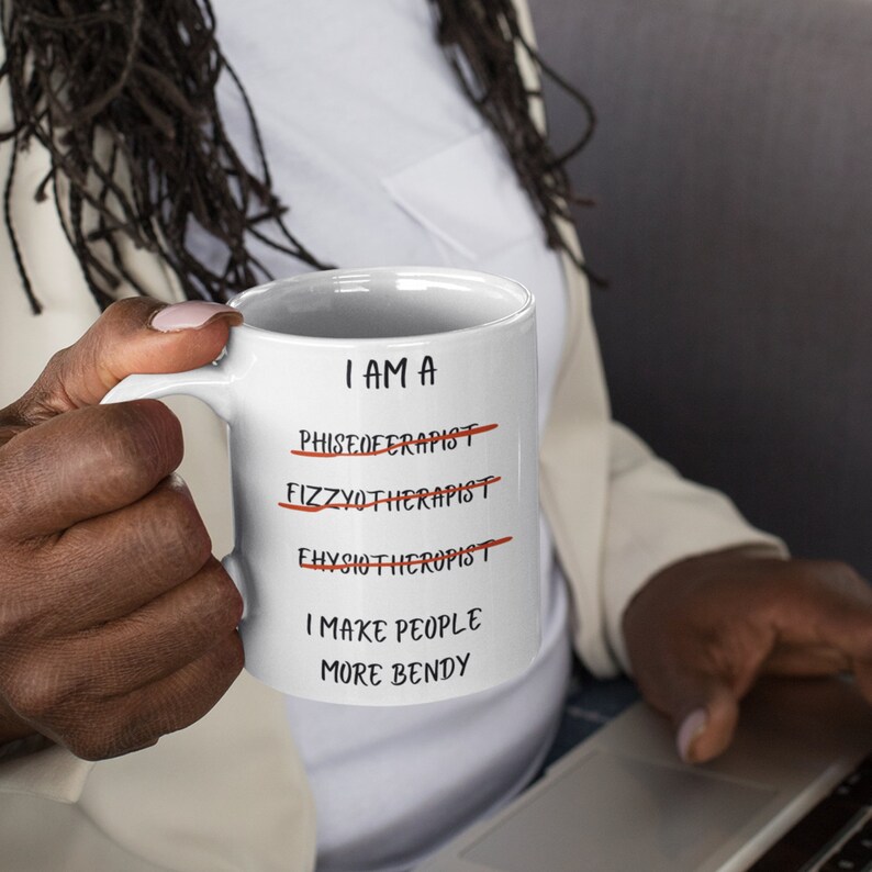 A white 11oz ceramic coffee mug for Physiotherapists with the funny caption "I am a Physiotherapist" But it is crossed out three times miss spelt. The caption then says at the bottom "I make people more bendy"