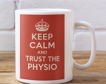 May include: White ceramic mug with a red rectangle featuring the text "KEEP CALM AND TRUST THE PHYSIO" in white, topped with a crown graphic. The mug has a curved handle.