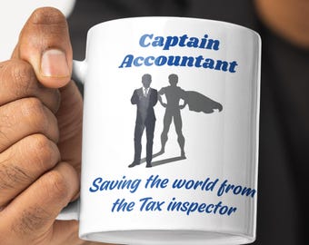 Może przedstawiać: Biały kubek ceramiczny z niebiesko-białym wzorem. Kubek przedstawia sylwetkę superbohatera-księgowego z tekstem "Captain Accountant" i "Saving the world from the Tax inspector".