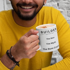 Puede incluir: Taza de cer&aacute;mica blanca con texto negro que dice "BUILDER The Man The Myth The Bum Crack!" Una persona est&aacute; sosteniendo la taza.