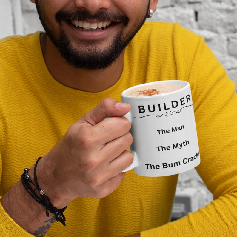 Puede incluir: Taza de cer&aacute;mica blanca con texto negro que dice "BUILDER The Man The Myth The Bum Crack!" Una persona est&aacute; sosteniendo la taza.