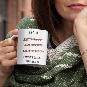 A white 11oz ceramic coffee mug for Physiotherapists with the funny caption "I am a Physiotherapist" But it is crossed out three times miss spelt. The caption then says at the bottom "I make people more bendy"