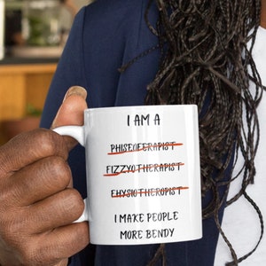 A white 11oz ceramic coffee mug for Physiotherapists with the funny caption "I am a Physiotherapist" But it is crossed out three times miss spelt. The caption then says at the bottom "I make people more bendy"