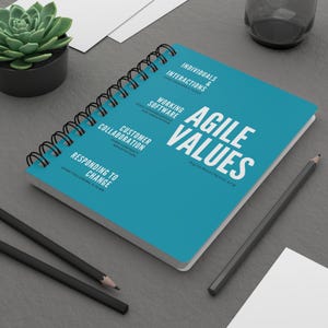 May include: A blue spiral bound notebook with the text "Agile Values" and the website address "AgileManifesto.org". The notebook lists the Agile values: Individuals and Interactions, Working Software, Customer Collaboration, Responding to Change.